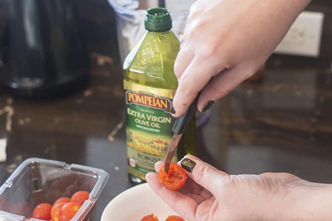Pop out the part you've cut from cherry tomato and gently squeeze out any seeds left inside.