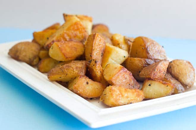 Roasted potatoes on a rectangular white platter.