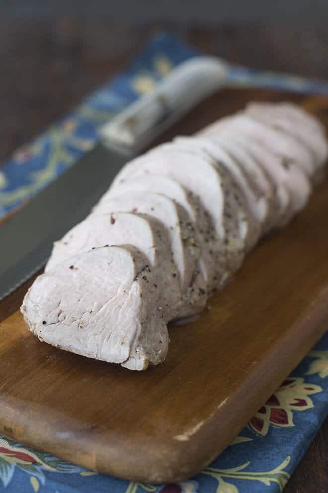 Sliced pork tenderloin on a cutting board.