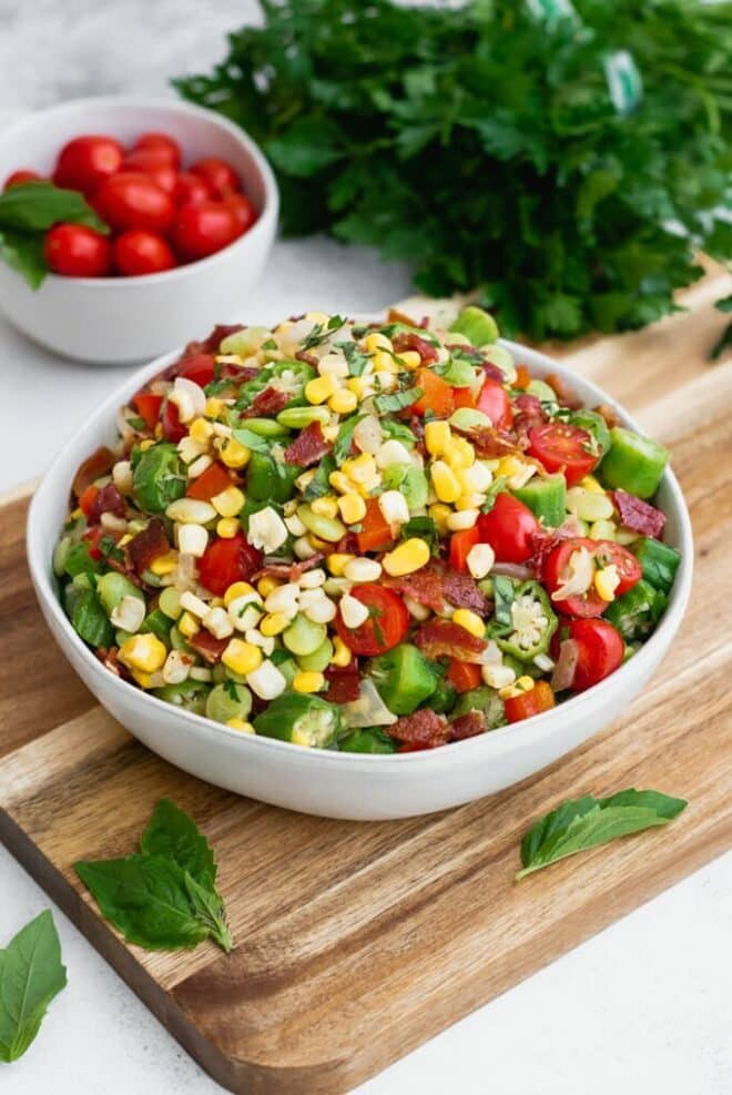 Succotash in a white bowl with corn, tomatoes, okra, and more.