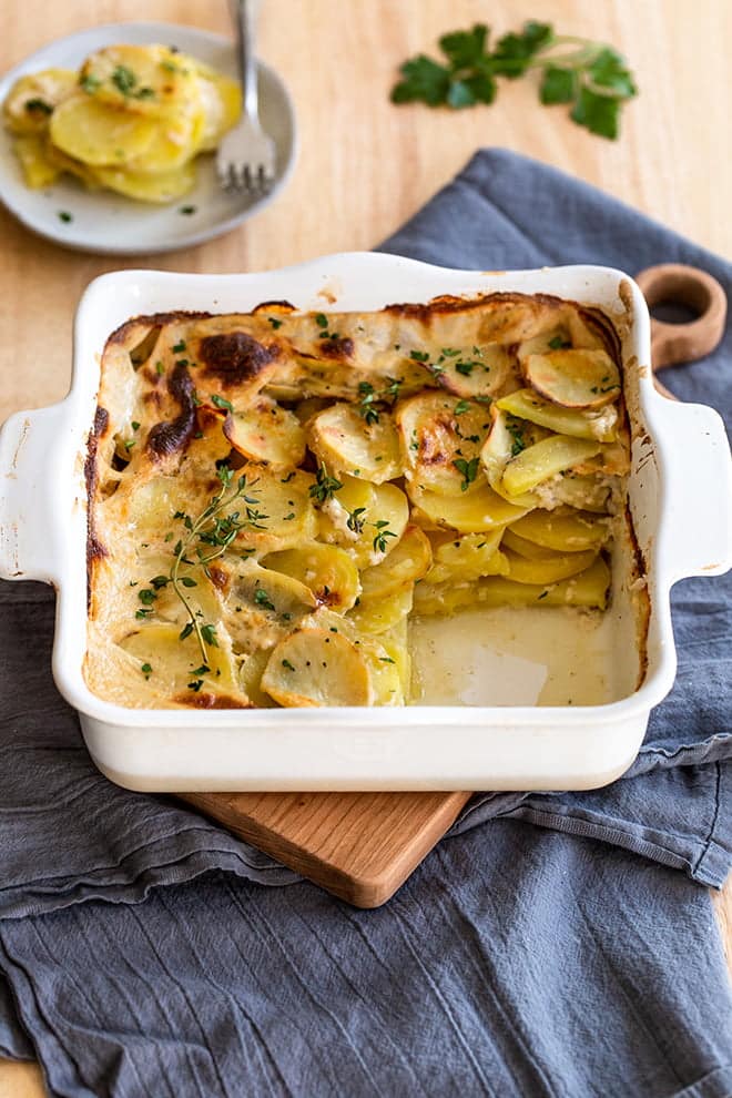 Classic scalloped potatoes in a white square baking dish.