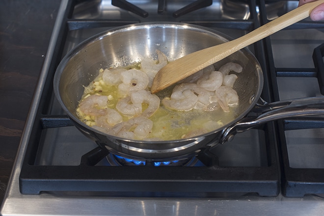 Peeled shrimp cooking in butter on the stove.
