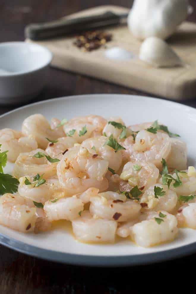 White plate of cooked shrimp with garlic and butter.
