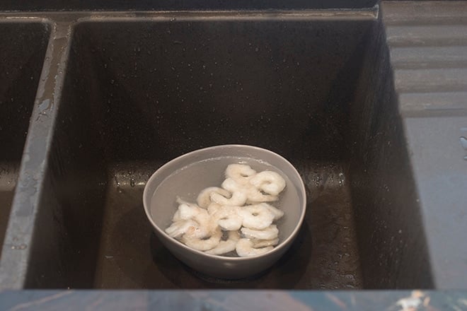 Frozen shrimp in a bowl with water.
