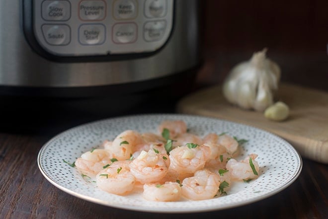 Cooked shrimp on a plate in front of an Instant Pot.