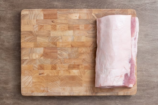 Raw pork loin on a wooden cutting board.