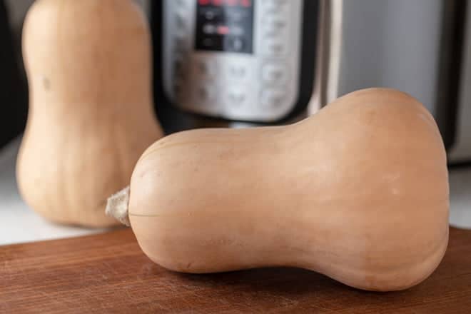 Whole butternut squashes in front of an instant pot.