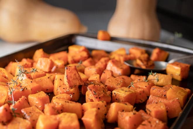 Cubed and roasted butternut squash on a baking sheet.