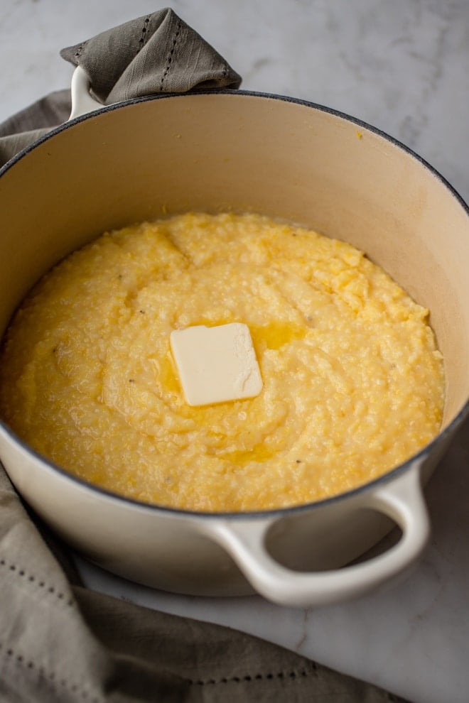 Grits in a dutch oven with a pat of butter melting on top.