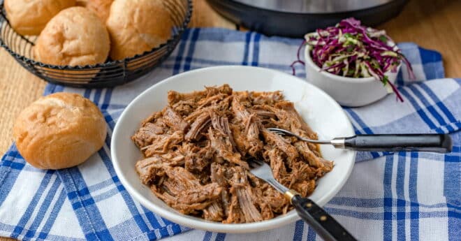 Pulled pork in a white dish with forks.