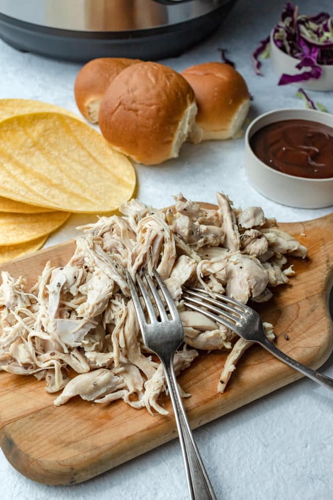 Pulled Chicken with forks on a wooden board.