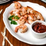 Roasted Shrimp on a white platter with a dish of red sauce.