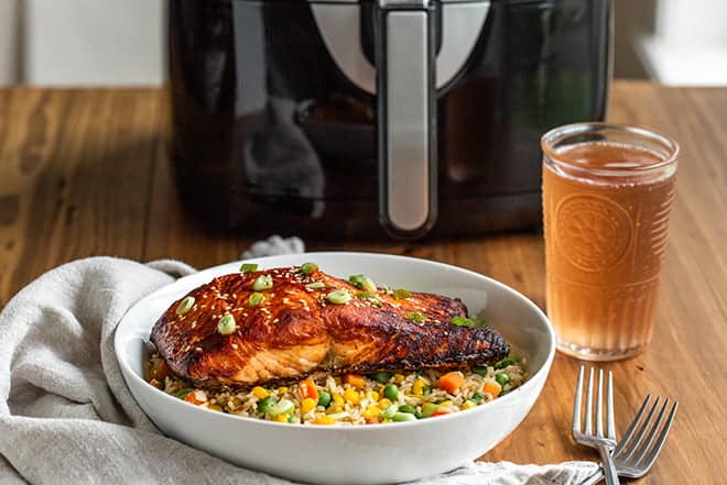 Salmon over fried rice in front of an air fryer.