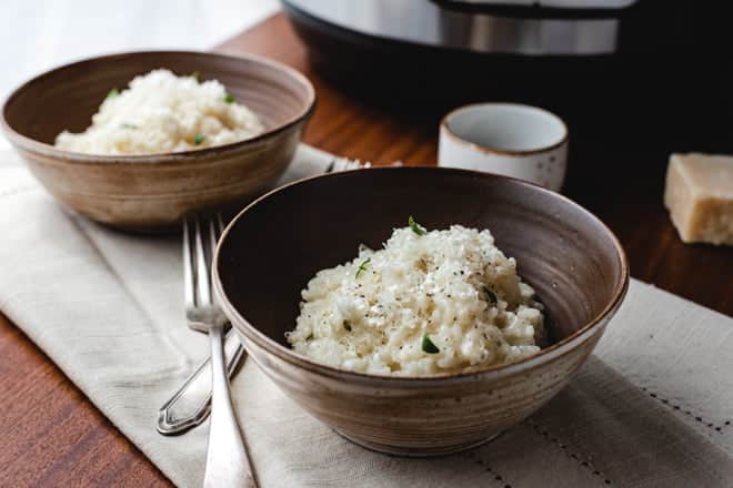 Bowls of risotto and forks in front of an instant pot.