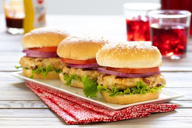 Turkey Burgers with lettuce, red onion, and tomato on a white platter.