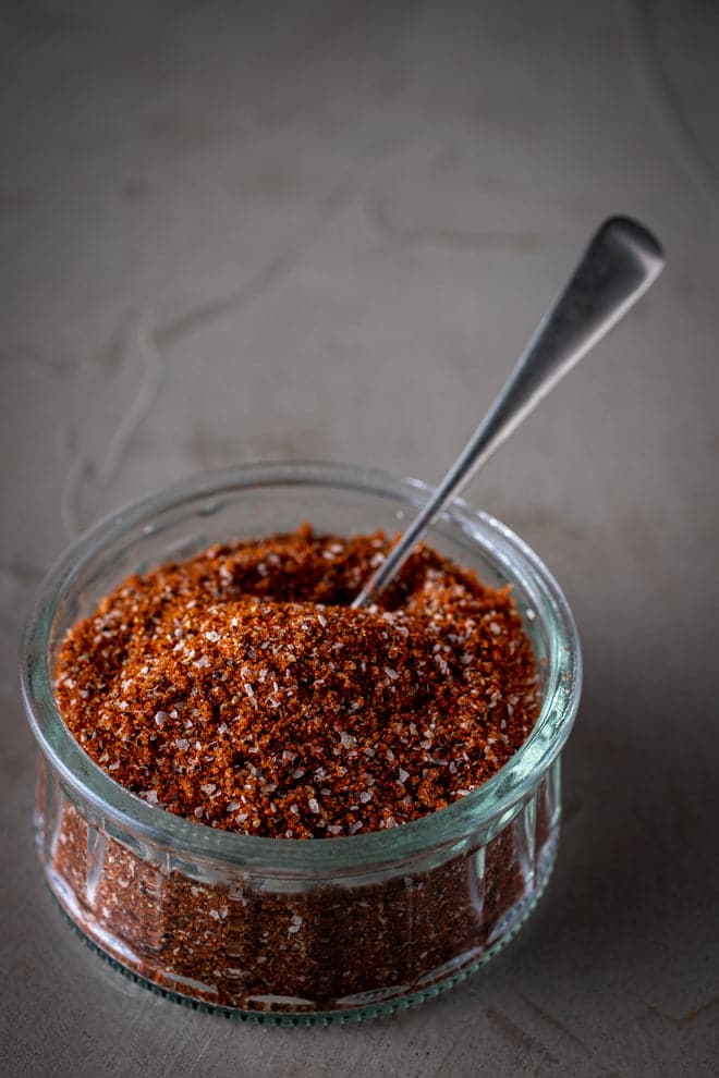 Glass container of Pork Rub Seasoning with spoon.