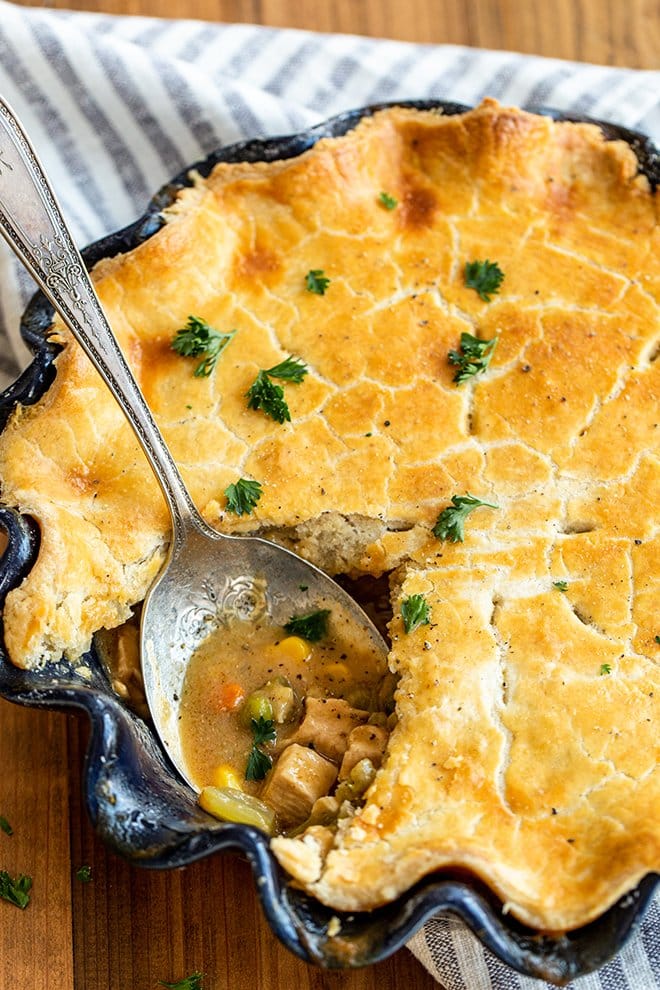 Chicken Pot Pie in a blue pie dish with a spoon.
