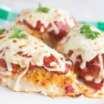 Chicken Breasts with breading, tomato sauce, and mozzarella cheese on a white plate.