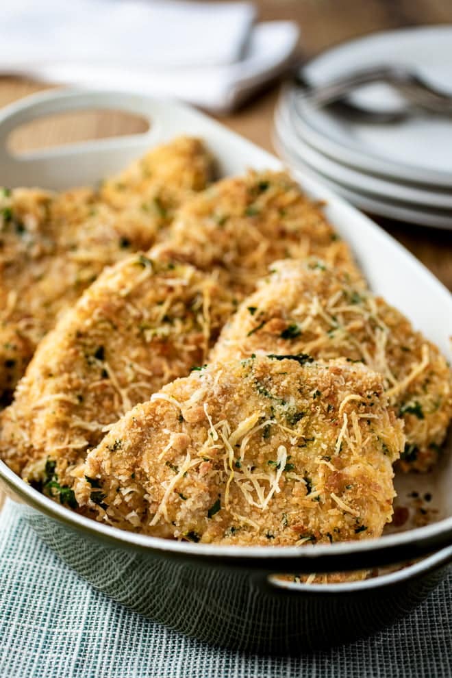 Breaded Parmesan chicken breasts in a white dish.