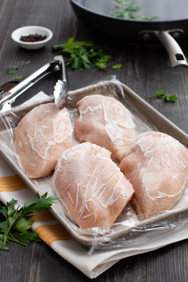 Frozen chicken breasts on a sheet pan.