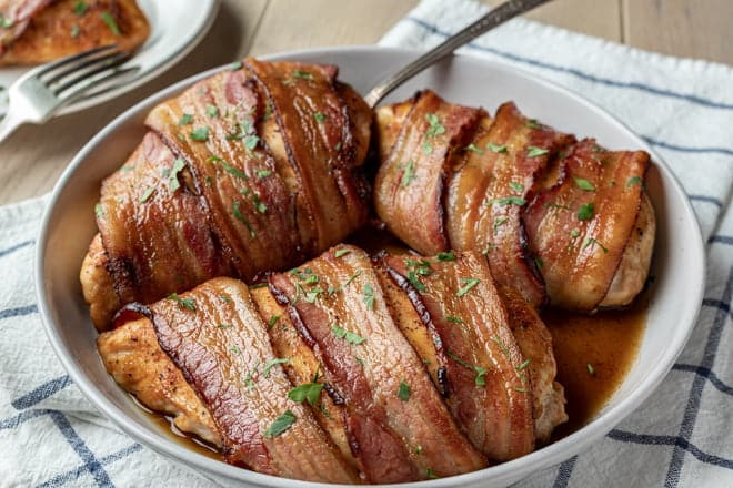 Bacon-wrapped chicken breasts in a white dish.