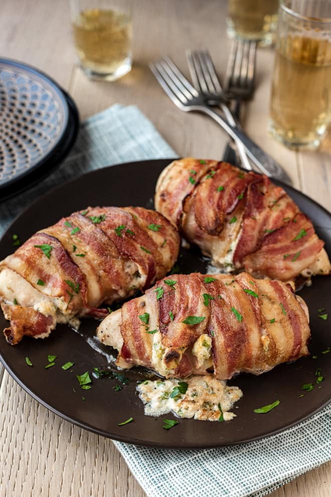 Jalapeño Popper Chicken Breasts wrapped in bacon on a black platter.