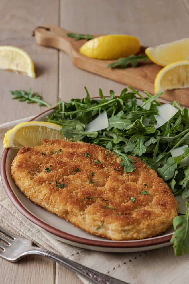 Crispy, juicy Chicken Milanese with a simple salad and a lemon wedge.