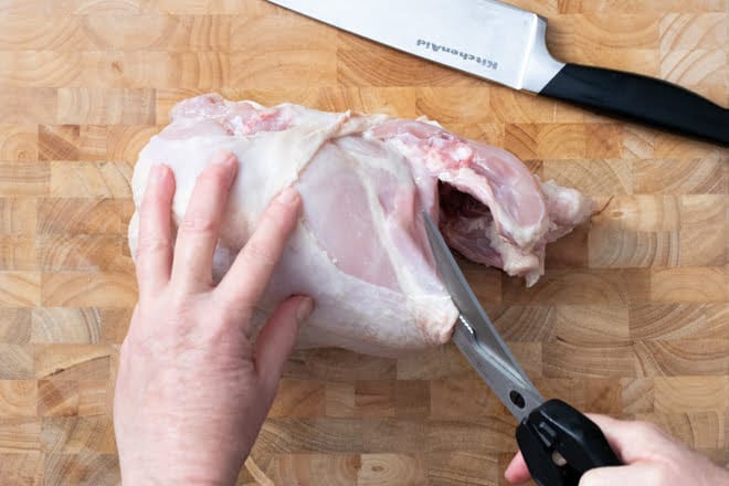 Separate the chicken breast from back by cutting from cavity to head opening.