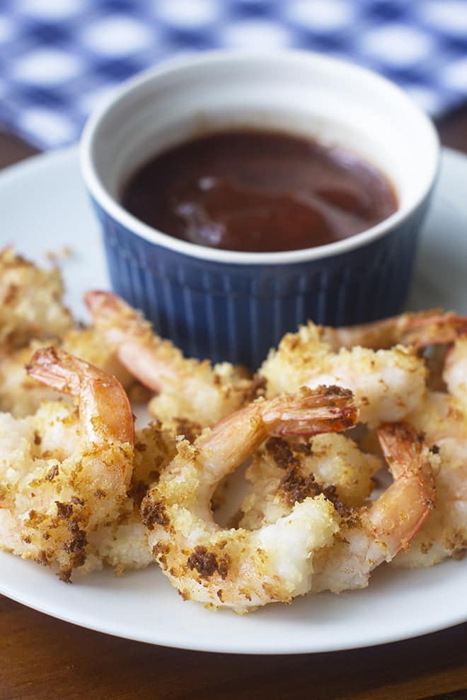 Breaded Shrimp on a white plate, with a small blue bowl of BBQ sauce.