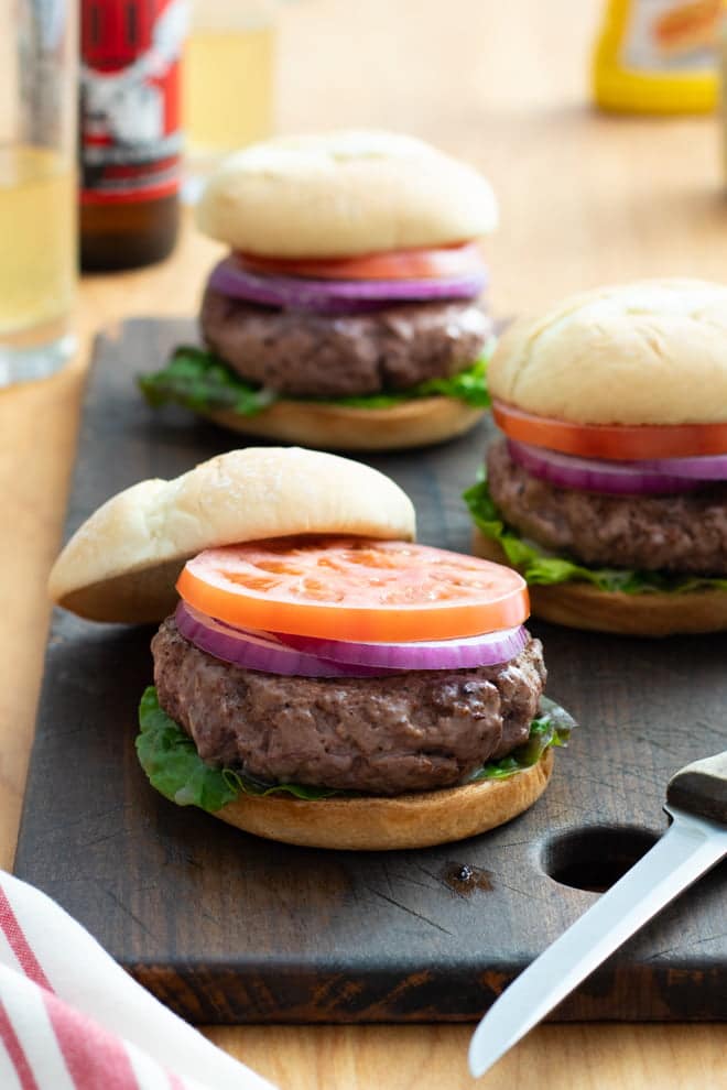 Steak Burgers on buns with lettuce, onion, and tomato.