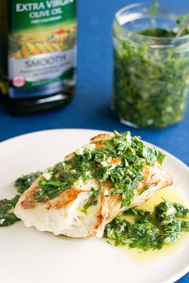 Italian salsa verde on fish served on a white plate.
