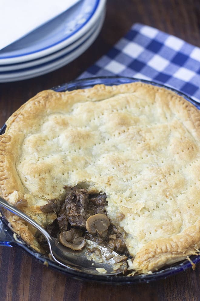 Steak and Mushroom Pie in a glass pie dish with spoon.