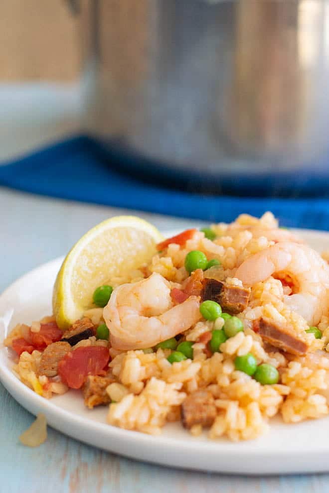 Instant Pot Paella on a white plate with a lemon wedge.