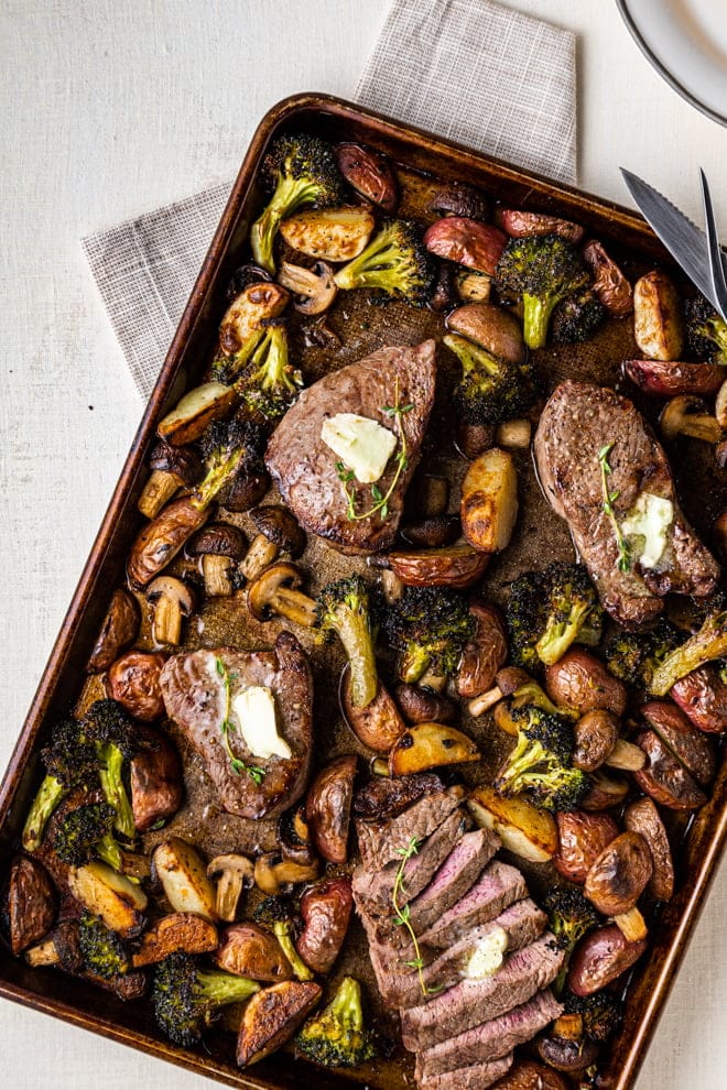 Tender, juicy steak surrounded by a colorful assortment of roasted vegetables is easy to pull-off any night of the week when you make it all on a sheet pan. Add some garlic butter and this becomes a special occasion meal.