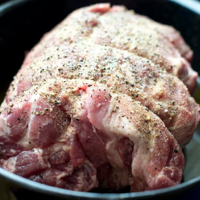 Raw seasoned pork roast in baking dish.