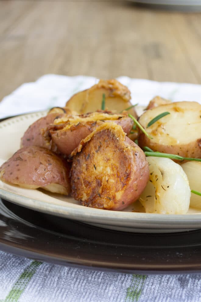 Halved red potatoes, onion wedges, all with a crispy Parmesan crust, garnished with chives