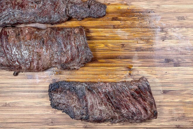 Cooked skirt steak on a cutting board.