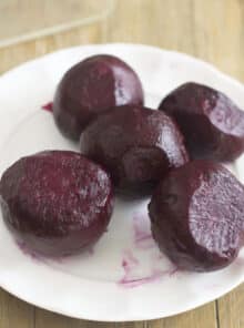 Five roasted beets on a white plate