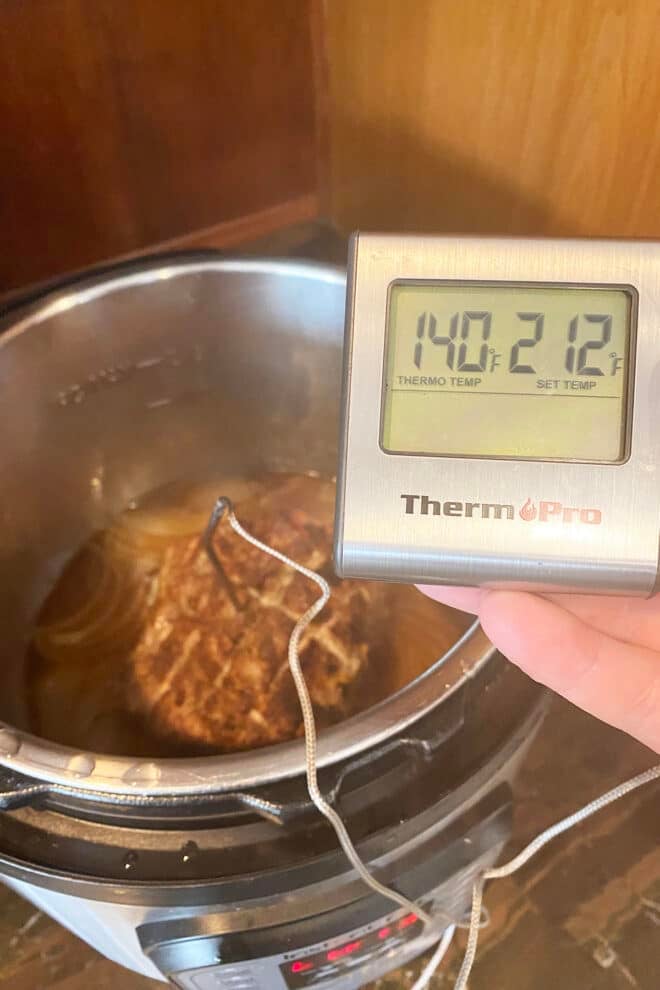I thermometer showing the temperature of a pork roast to be 140F.