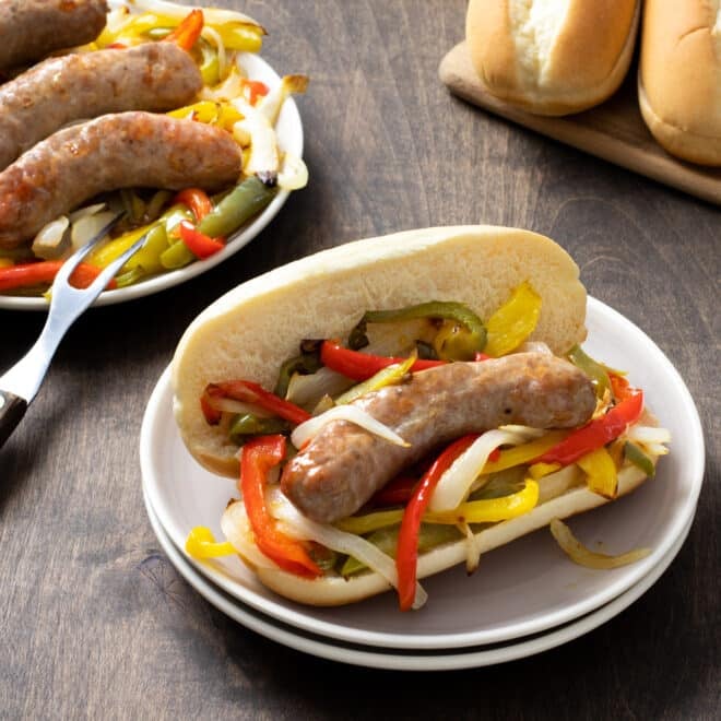 sausage and pepper hoagie on white plate.