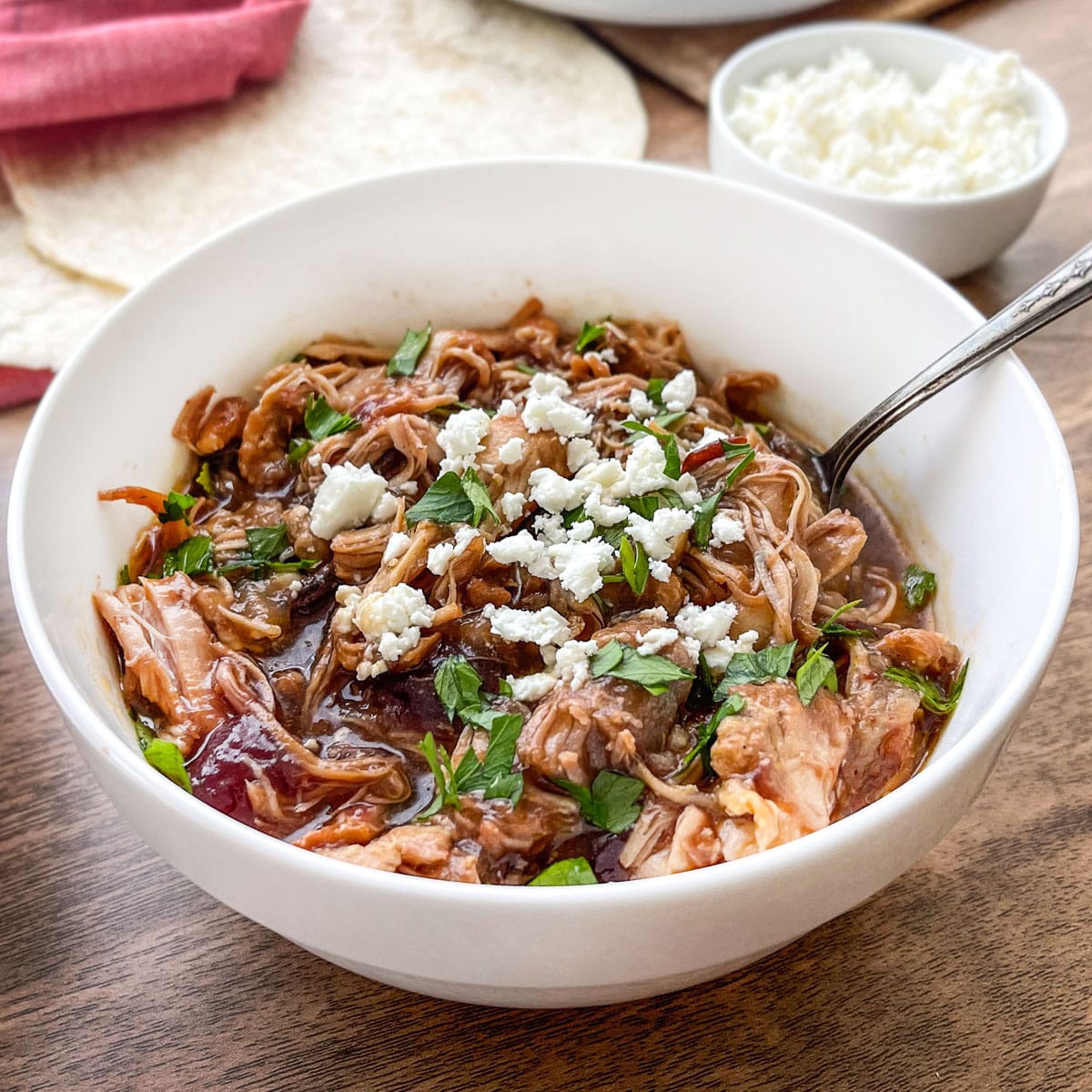 White bowl of cranberry chipotle shredded chicken