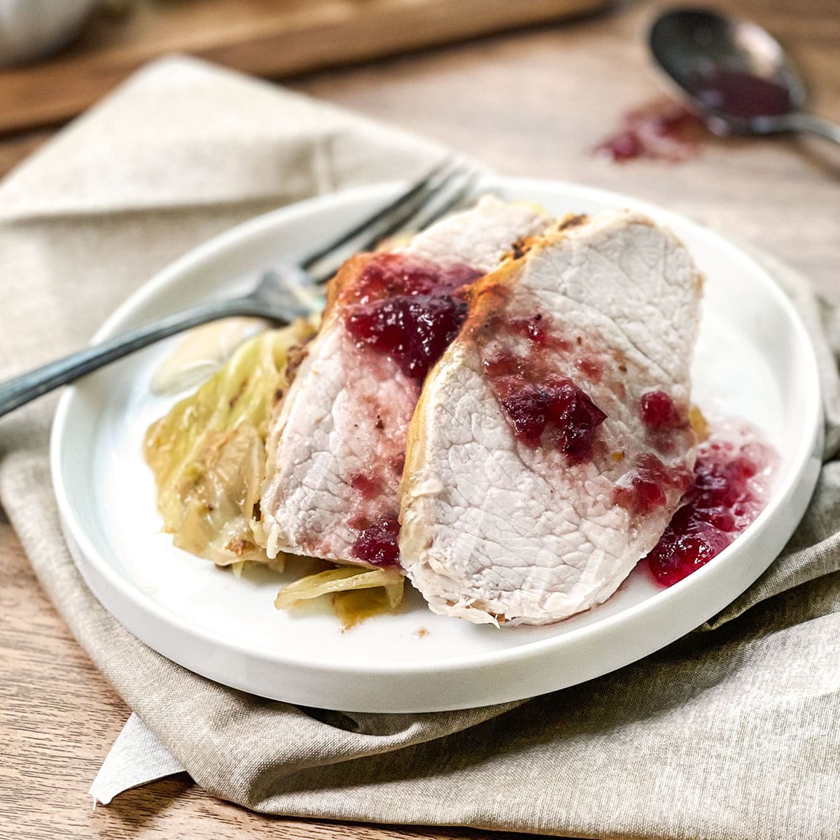 Slices of pork with cranberry sauce on top of cabbage.