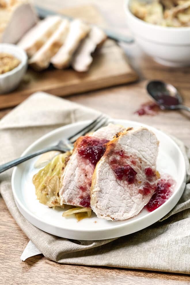 Slices of pork loin over cabbage, with a cranberry sauce on top.