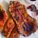 Halved butternut squash, roasted and covered with cranberry glaze. One half cut into slices.