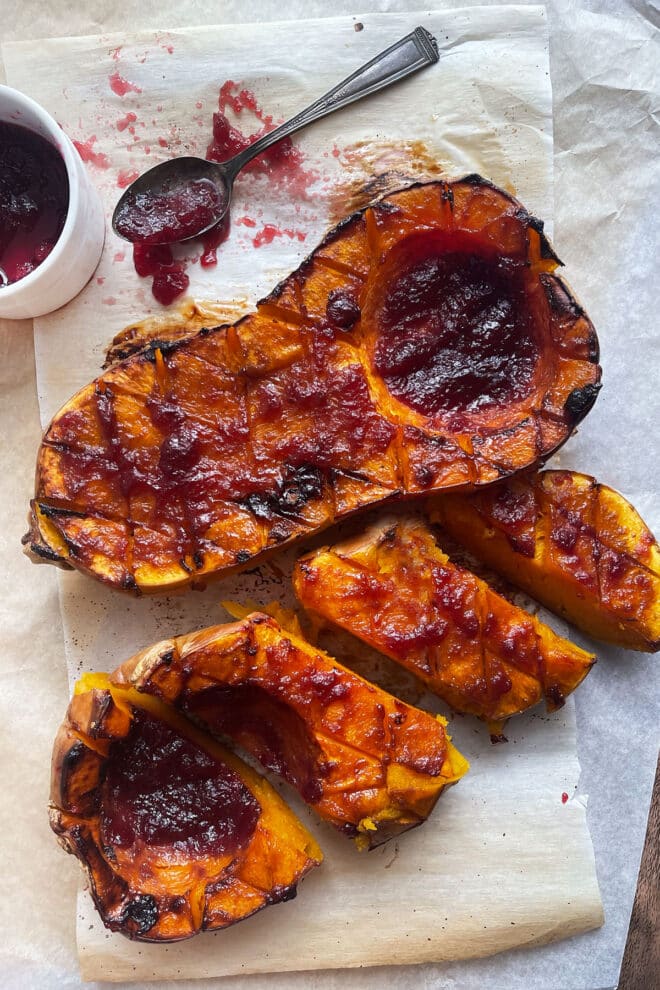 Halved butternut squash, roasted and covered with cranberry glaze. One half cut into slices.