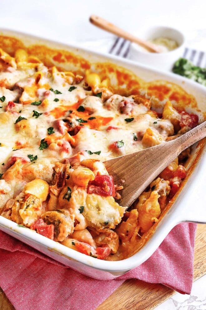 Cheesy Pasta Bake in a white casserole dish with wooden spoon in it.