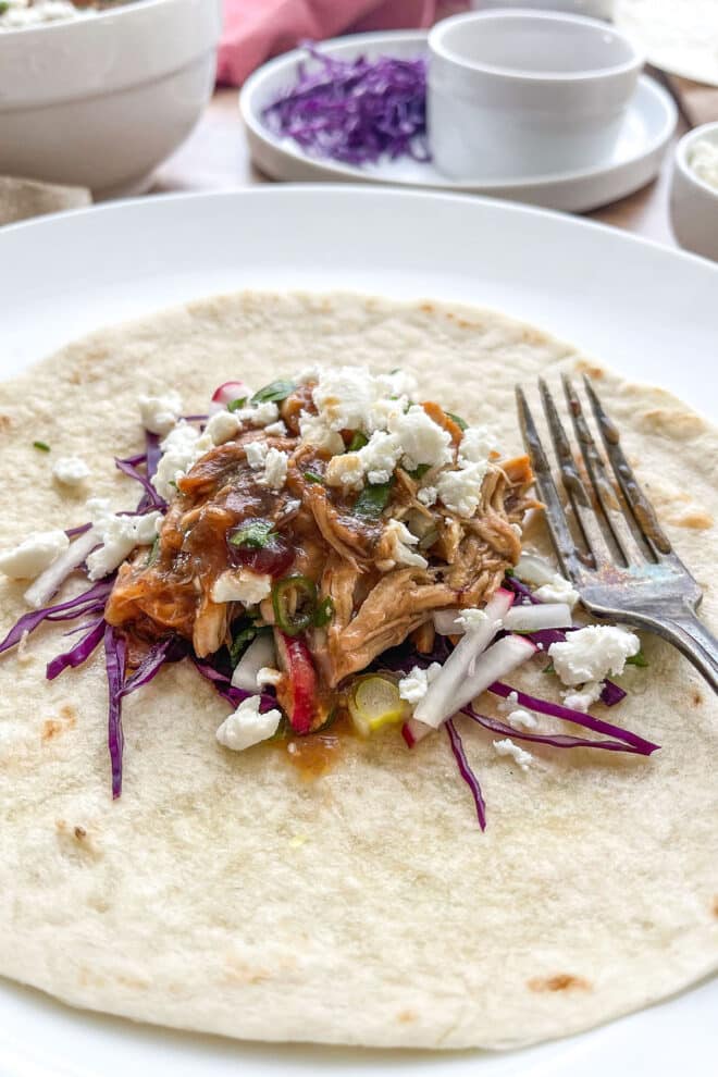 Soft taco with cranberry chipotle pulled chicken, cabbage, and queso fresco.