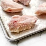 Frozen chicken wings on a baking sheet.