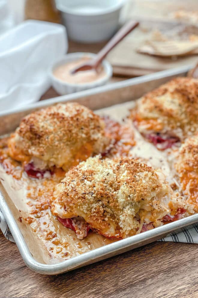 Baking sheet of chicken thighs stacked with corned beef, sauerkraut, and crispy breadcrumbs.