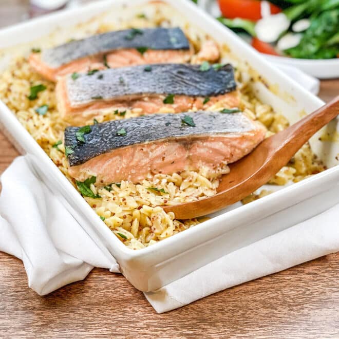 White rectangular dish with orzo and salmon fillets.